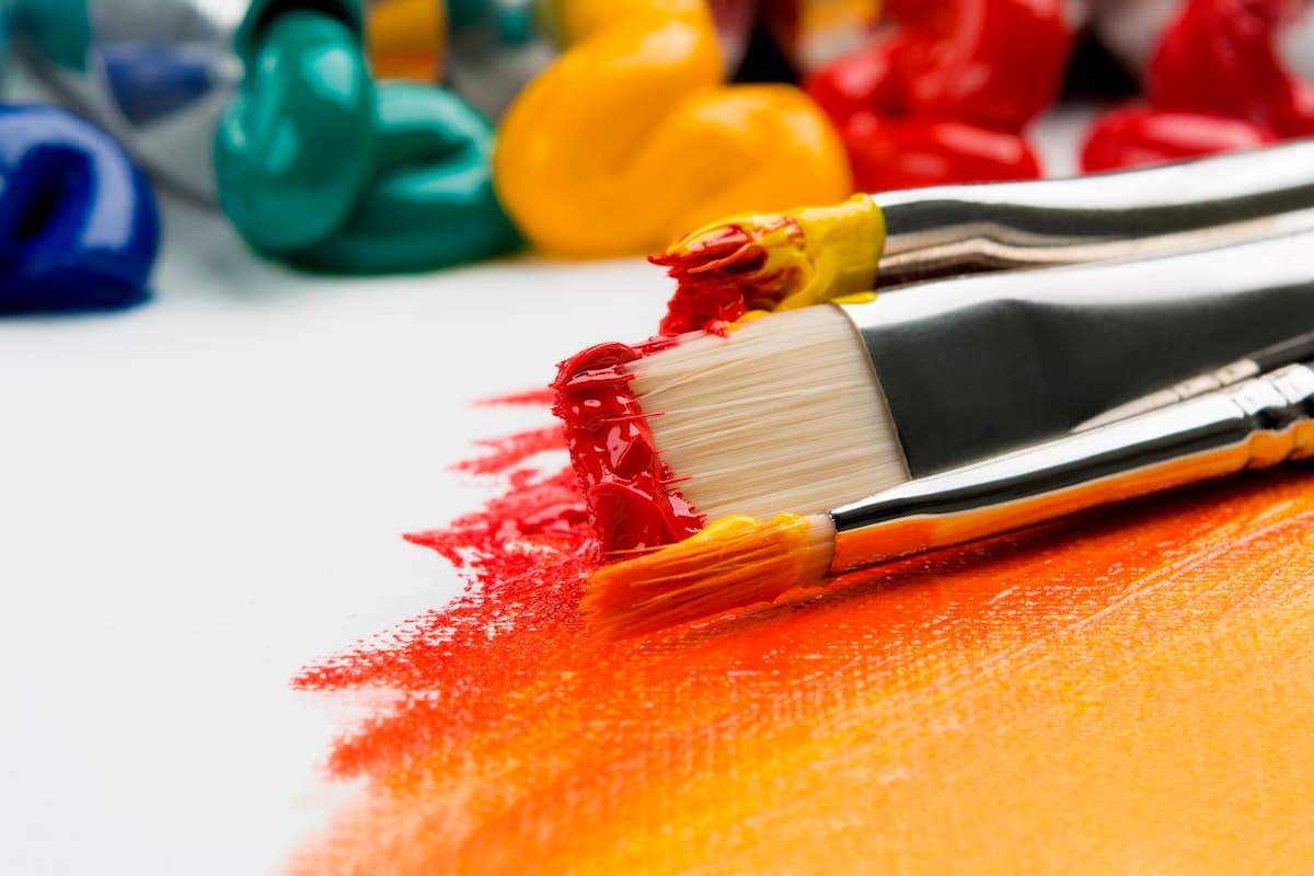 Close-up of paint brushes with colorful acrylic paint strokes on a white canvas