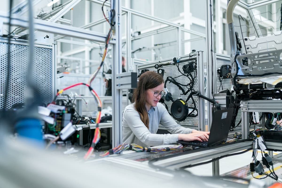 Engineer working on a laptop surrounded by wiring and electronics in an industrial lab