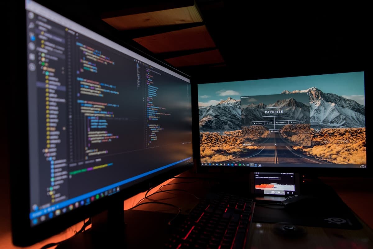 Two computer monitors displaying lines of code in a dark development environment