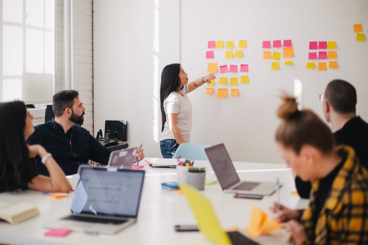 Team planning session around a table with colorful sticky notes arranged on a white wall