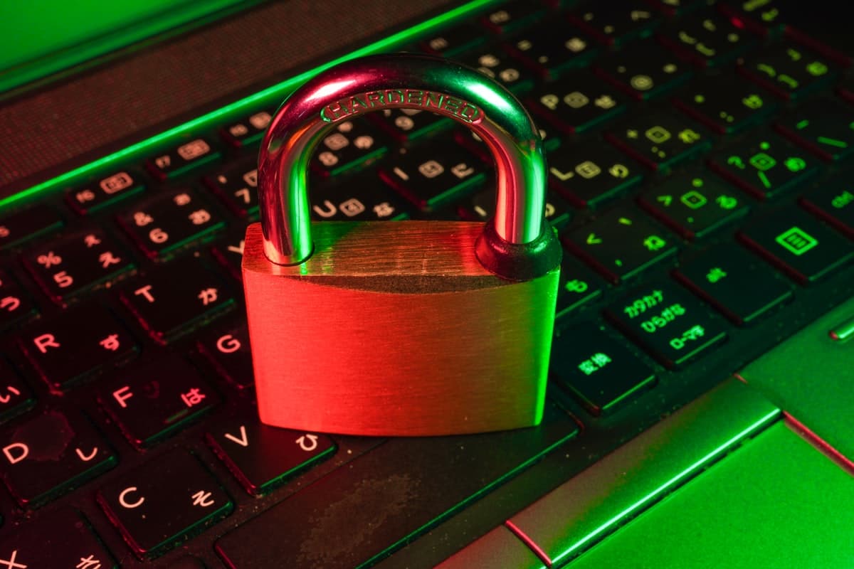 A brass padlock resting on a laptop keyboard illuminated by red and green light representing data security