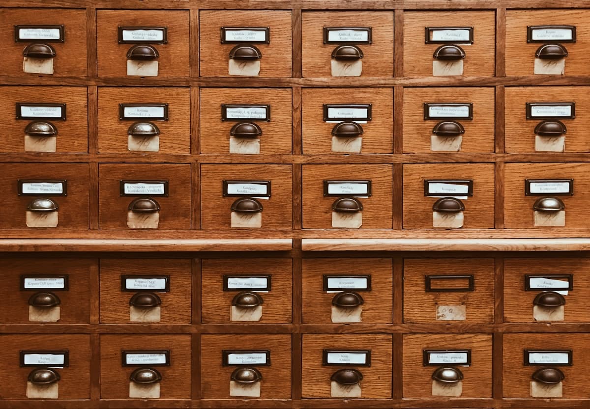 Vintage library card catalog with labeled wooden drawers in warm lighting