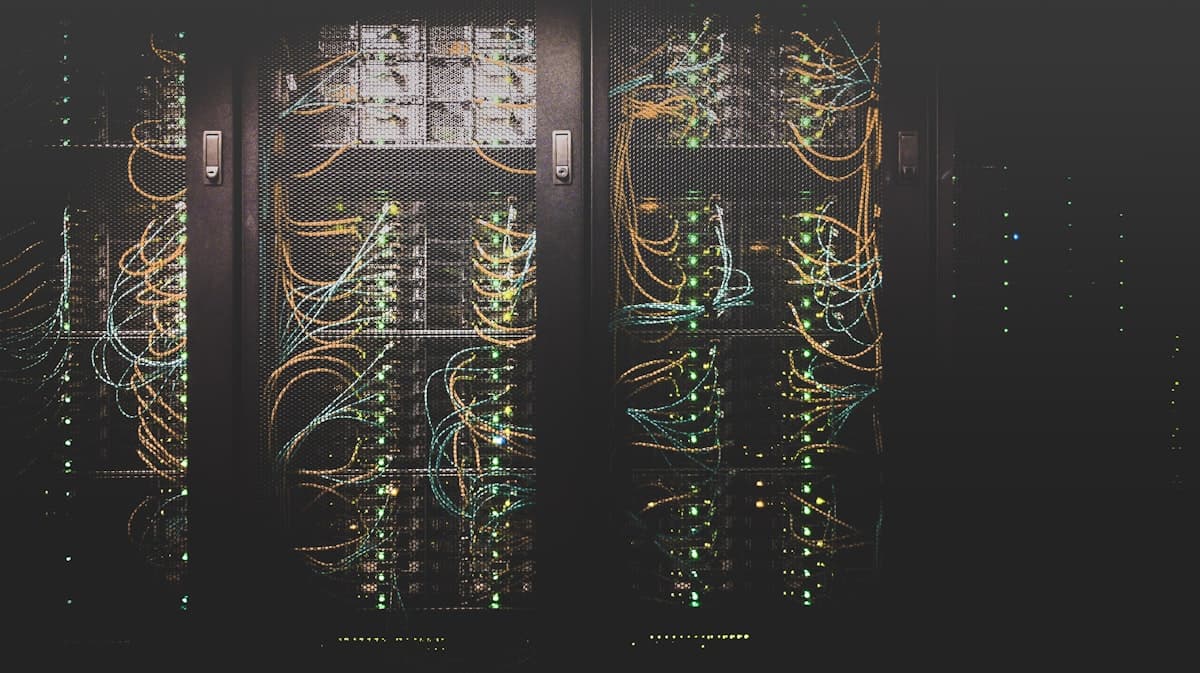 Server rack with glowing green lights and network cables in a dark data center
