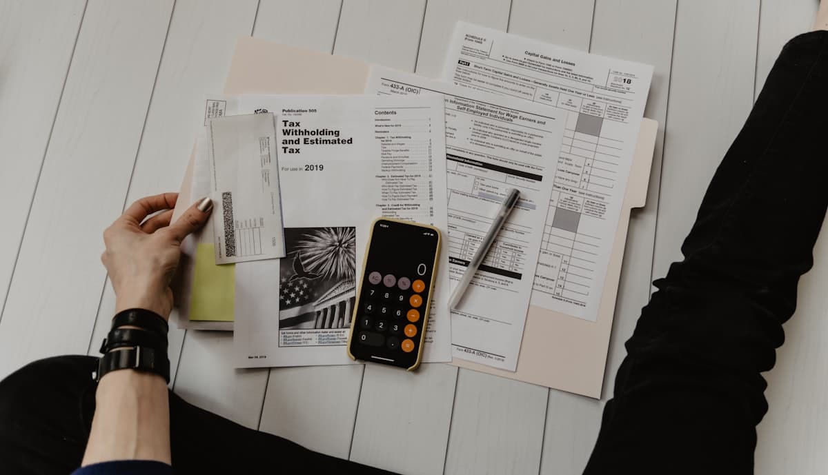 Person holding paper near a pen and calculator reviewing financial documents